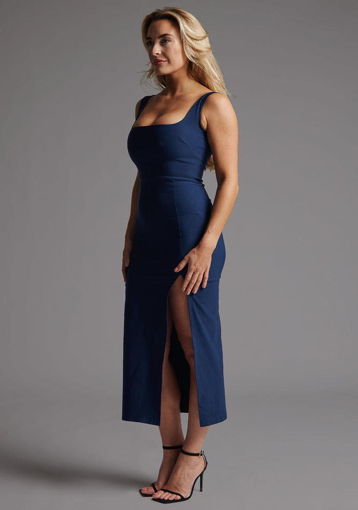 Side front image of a model wearing the Vesper Abbie Square Neck Midaxi Dress in Navy, highlighting the sculpting fit and fluid fabric movement