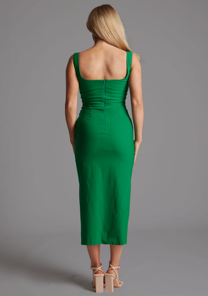 Back image of the model wearing a emerald bodycon midaxi dress with a square neckline and a front split. The design featured is the Vesper Abbie Emerald Midaxi Dress