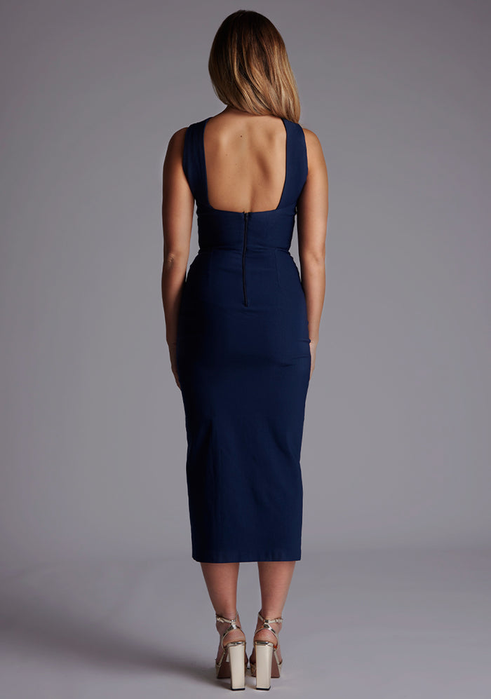 Back image of a model wearing the Vesper Aida Cross Neck Midaxi Dress in Navy, featuring an open-back design and clean, modern lines