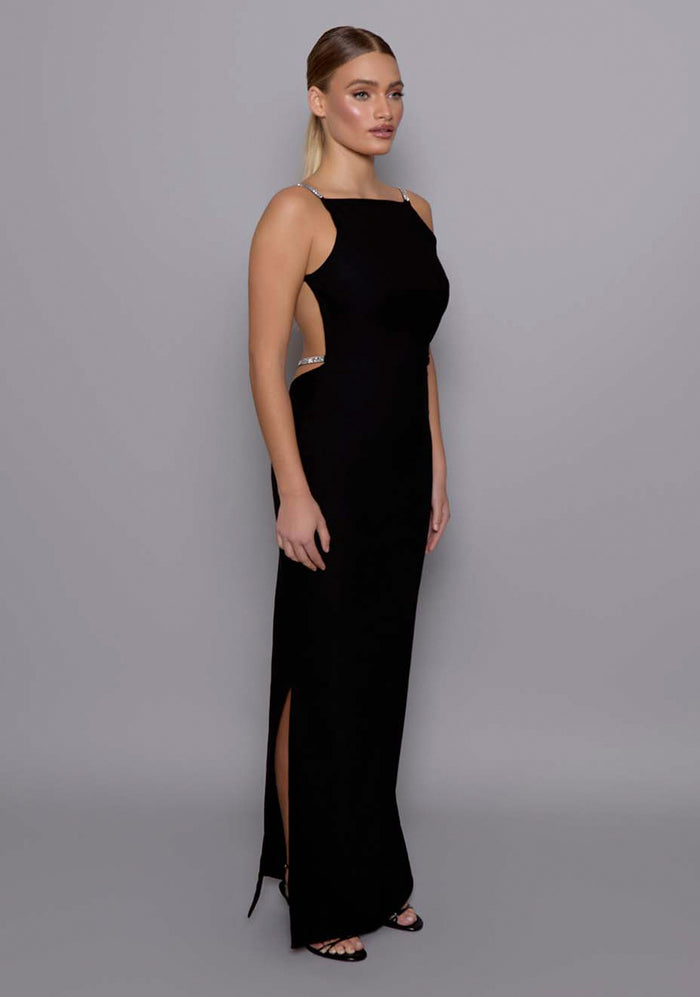 Side front image of a model wearing  the VSPR Alba Open Back Maxi Dress in Black, revealing the elegant profile, square neckline, and sculpted waistline with clean, elongating lines.