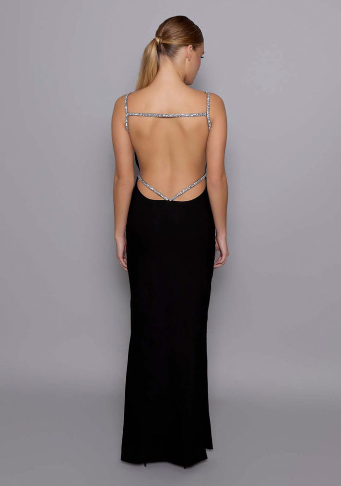 Back image of a model wearing the VSPR Alba Open Back Maxi Dress in Black displaying the dramatic open-back design with silver crystal-embellished straps, capturing the refined glamour.