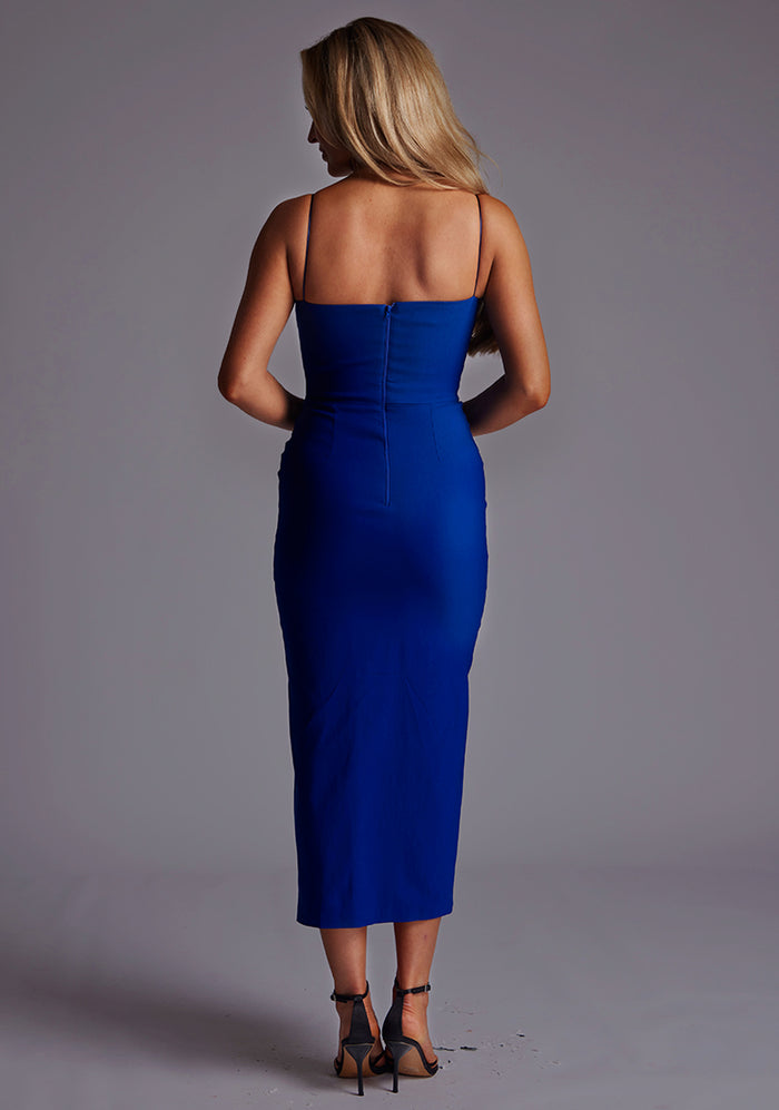 Back image of a model wearing a cobalt midaxi dress with a charming sweetheart neckline with a ruched front design, delicate thin straps and graceful front skirt split. The design featured is the Vesper Alex Cobalt Midaxi Dress