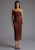 Front image of a model wearing the Vesper Andorra Strapless Midaxi Dress in Chocolate, featuring a sleek strapless neckline, slim-fit silhouette, and elegant front skirt split, posed against a grey studio backdrop.