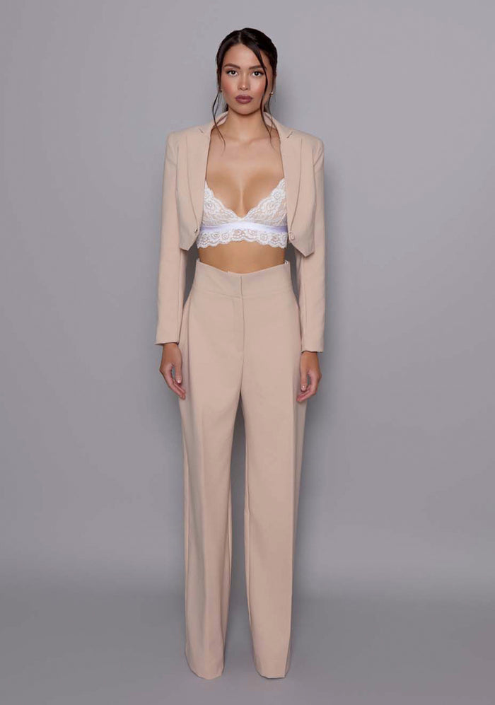 Model wearing the VSPR Aria cropped tailored Jacket in Stone, featuring sharp lapels, sculpted waist, and clean architectural lines, against a neutral gray studio backdrop.