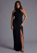 Front image of a model wearing the Vesper Ariella High Neck Maxi Dress in Black featuring a sleek high halter neckline, front skirt split, and elegant maxi length silhouette, posed against a grey studio backdrop.