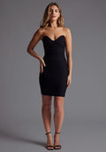 Front image of a model wearing the Vesper Arizona Strapless Bodycon Mini Dress in Black with a strapless sweetheart neckline and fitted mini silhouette, standing against a grey studio backdrop.