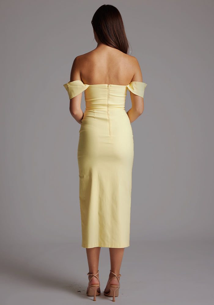Back image of a model wearing a yellow Bardot midaxi dress with a stunning Bardot neckline with armbands and a front skirt split. The design featured is the VSPR Astra Yellow Bardot Midaxi Dress.