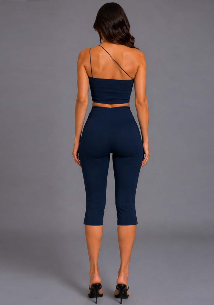 Back image of a model wearing the VSPR Avalon Asymmetric Strap Navy Crop Top with a clean, streamlined back profile and flattering fitted silhouette, standing against a grey studio backdrop.