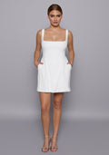 Model wearing the VSPR Camille Ivory Mini Dress featuring a structured square neckline and wide straps, with a soft A-line skirt, posed against a neutral studio backdrop