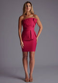 Front image of a model wearing the Vesper Cecilia Pleated Strapless Mini Dress in Cerise, featuring a sleek strapless neckline, structured pleats, and a defined mini-length silhouette, staing against a grey studio backdrop.