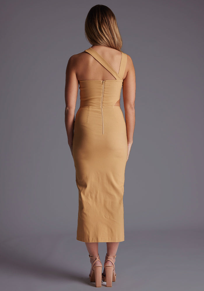 Back image of a blonde model wearing a coffee midaxi dress with a one shoulder design, tasteful cutout detailing, and a front skirt split. The design featured is the Vesper Cerellia Iced Coffee Midaxi Dress.