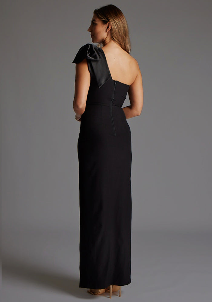 Side back image of a model wearing the Vesper Ceylon One Shoulder Bow Maxi Dress in Black, highlighting the smooth back line and refined one-shoulder construction.