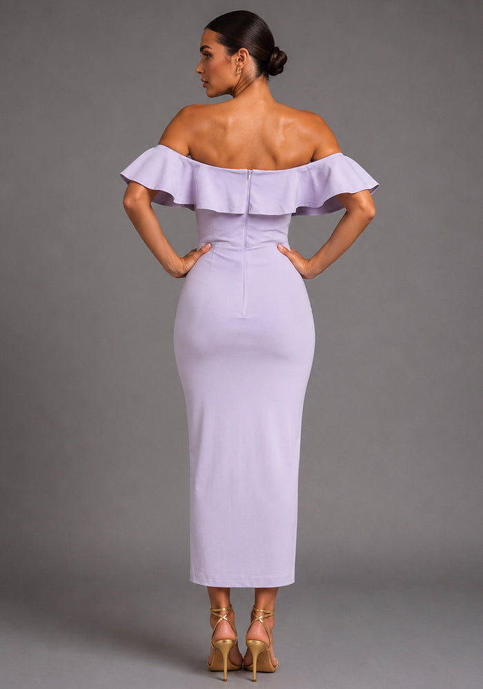 Back image of a model wearing the VSPR Deirdre Bardot Off-Shoulder Frill Lilac Midaxi Dress showcasing the off-shoulder Bardot neckline, feminine frill detailing, and sleek fitted silhouette against a grey studio backdrop.