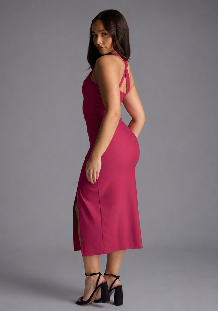 Woman wearing the Vesper Petite Nellie cerise notch neck midaxi dress against a grey background, side back view