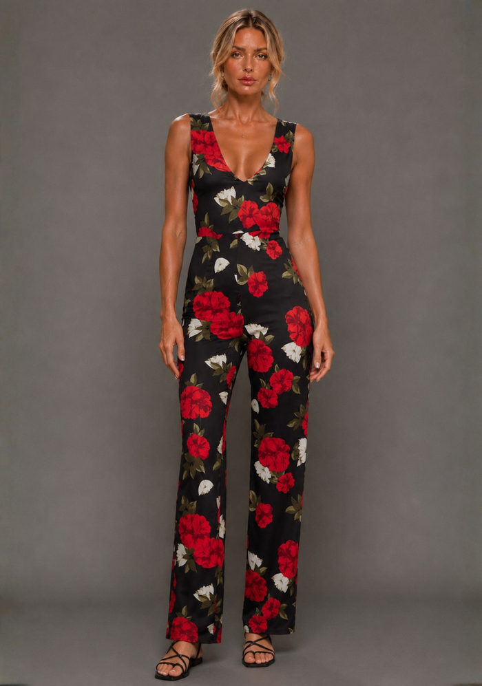 Front view of a model wearing the VSPR Noelle Black Floral Wide Leg Jumpsuit featuring a flattering V neckline, oversized floral print, and flowing wide leg trousers against a grey studio backdrop.